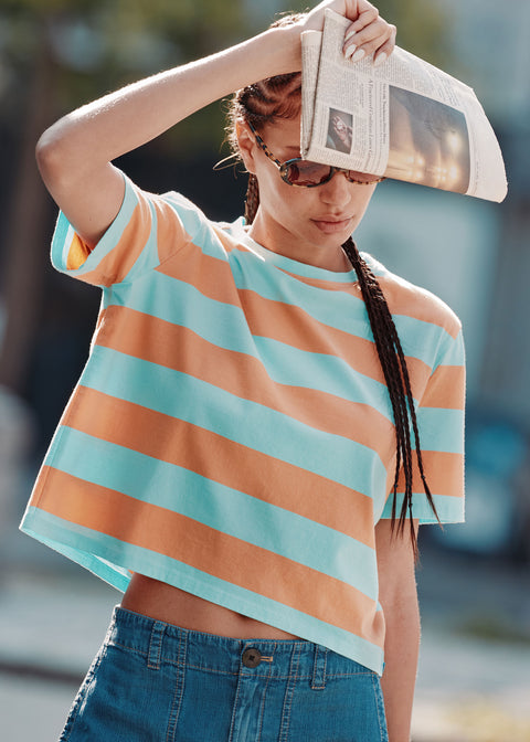 Model wearing the Brentwood tee in sherbert/aqua with the Chambray City pants holding a newspaper over her face