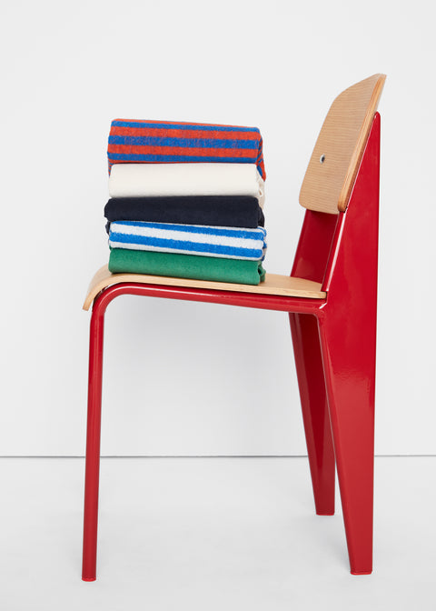 Red and wooden modern chair with stack of colorful terry clothes folded