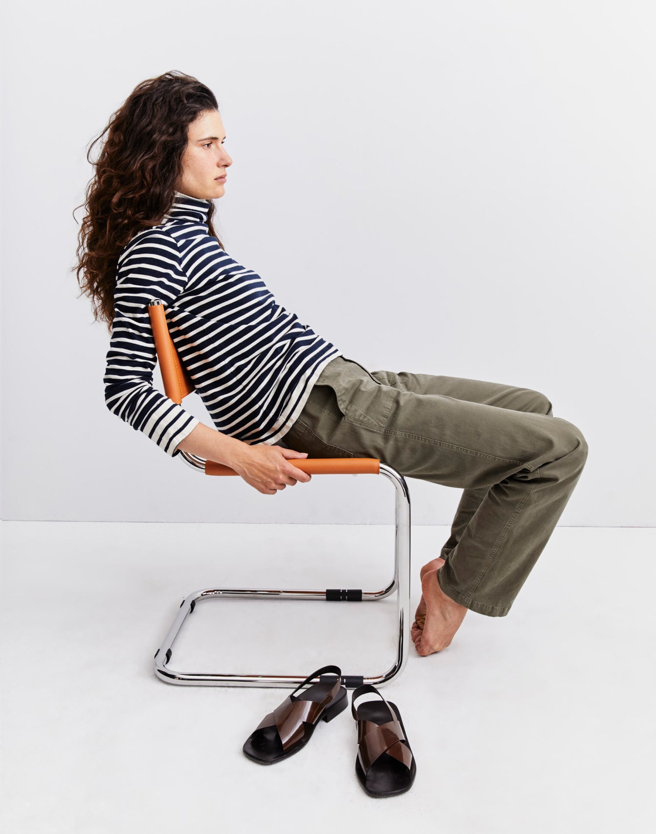 Model leaning back in a chair wearing The Turtleneck - Navy/Cream layered over The Turtleneck - Cream/Navy