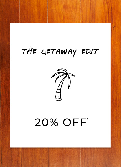 Promotional sign for 'The Getaway Edit' with a palm tree graphic and 20% off text on a wooden background.