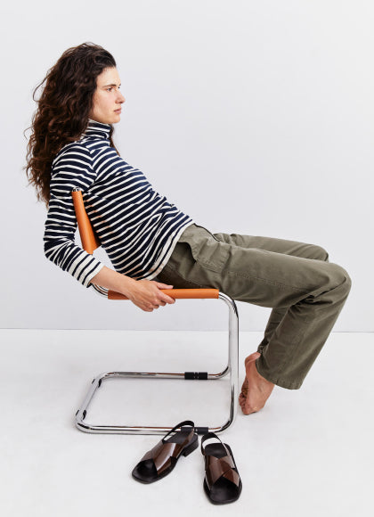 Model sitting on a chair with a white background wearing The Turtleneck - Navy/Cream