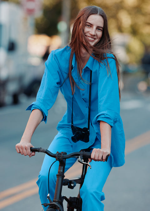 Female model riding a bike wearing the Blanca shirt and City pants in blue