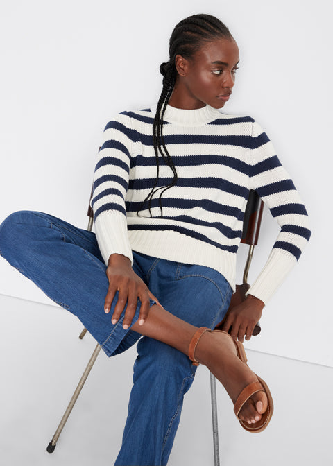 Model sitting in a chair wearing the Tatum sweater in cream/navy with the Chambray City pants in dark denim